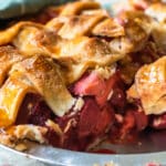 A strawberry rhubarb pie in a pie pan with one slice removed.
