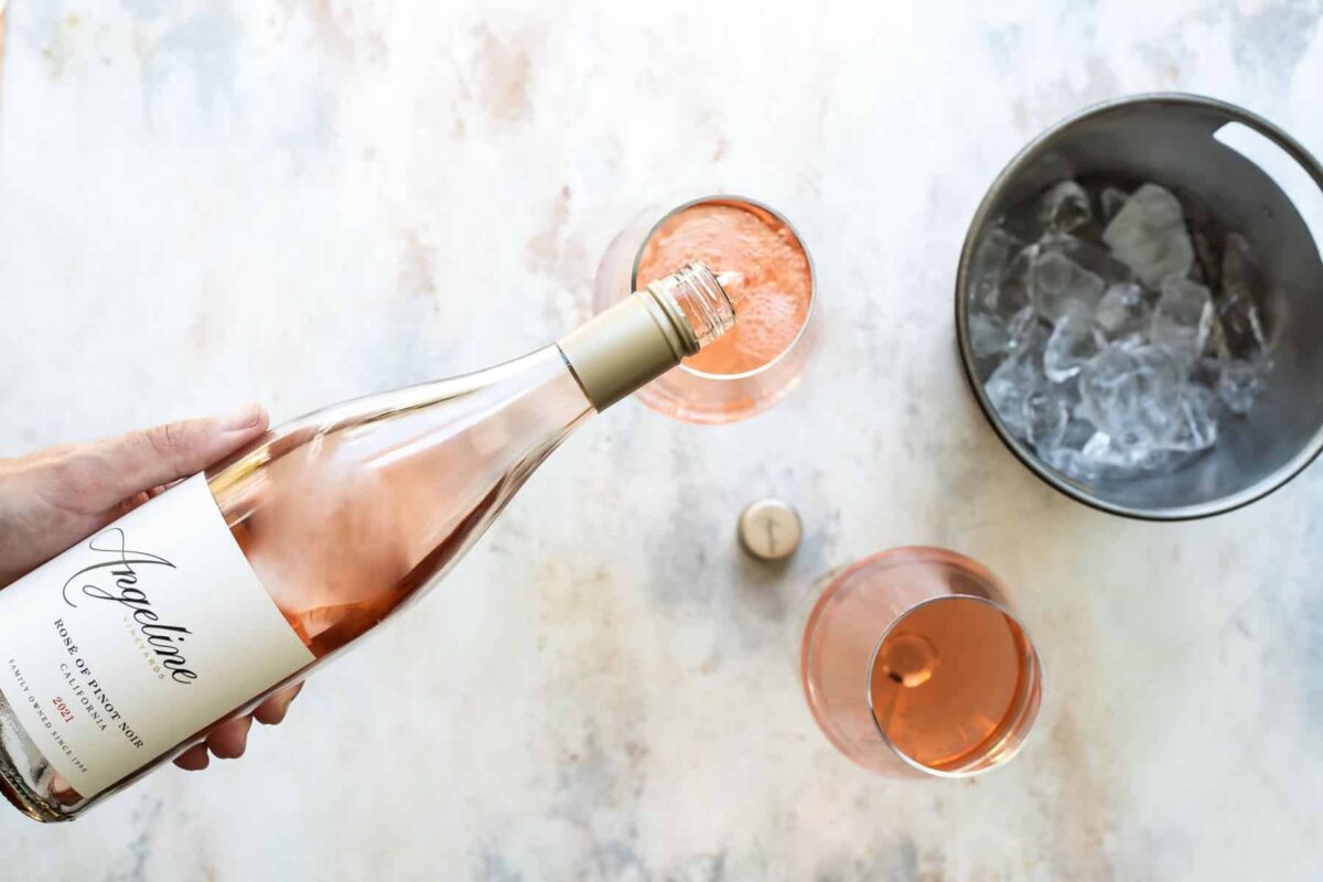 Somebody pouring two glasses of rose wine.
