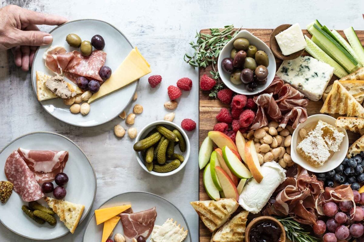 A charcuterie board filled with meats, cheese, fruits, nuts, crackers, and other snacks.