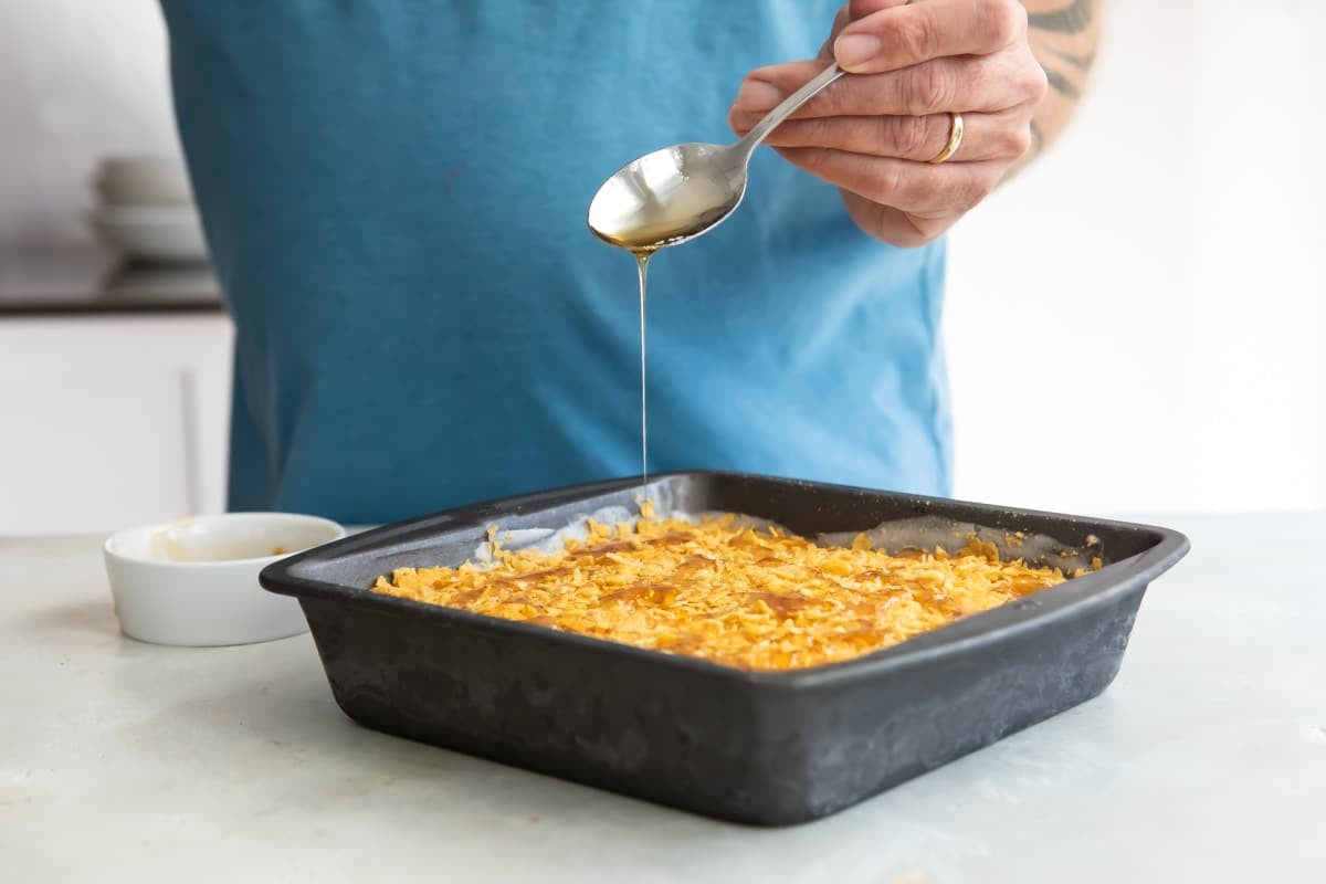 Drizzling honey over corn flakes on ice cream.