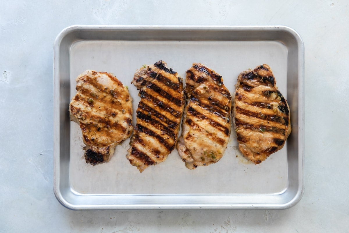 Grilled pork chops on a baking sheet.