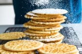 Pizzelle cookies being dusted with powdered sugar.