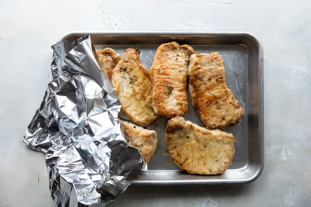Pork cutlets on a baking sheet.