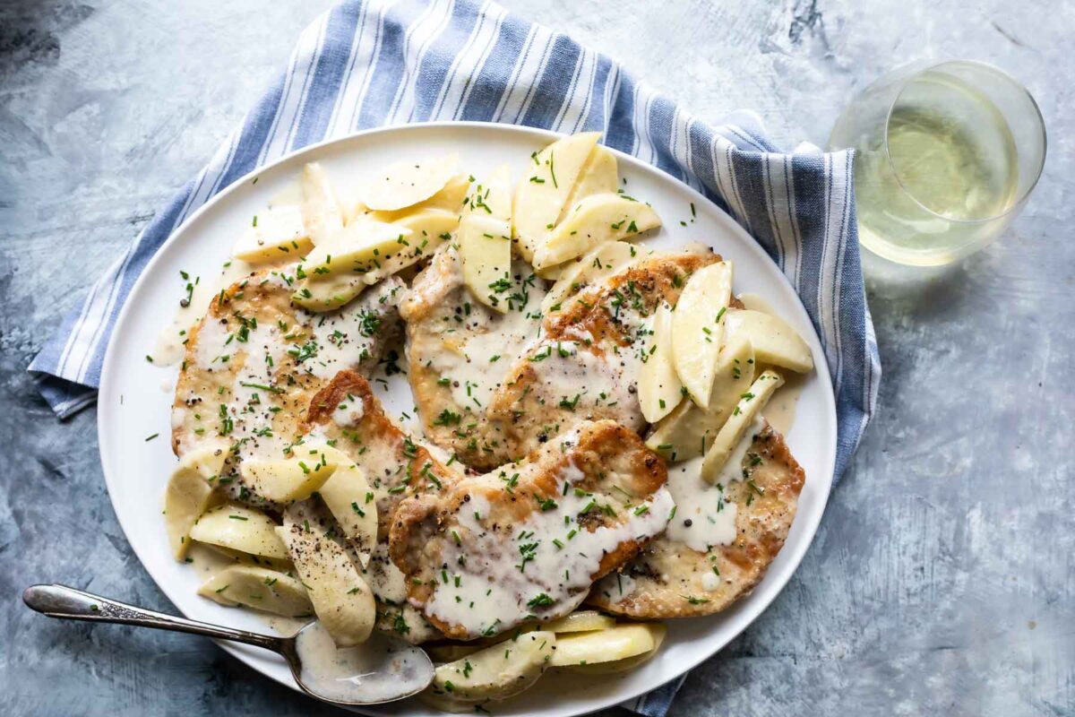 Pork cutlets and apples on a platter.