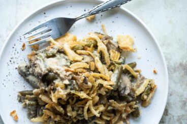 Vegan green bean casserole on a plate with a fork.