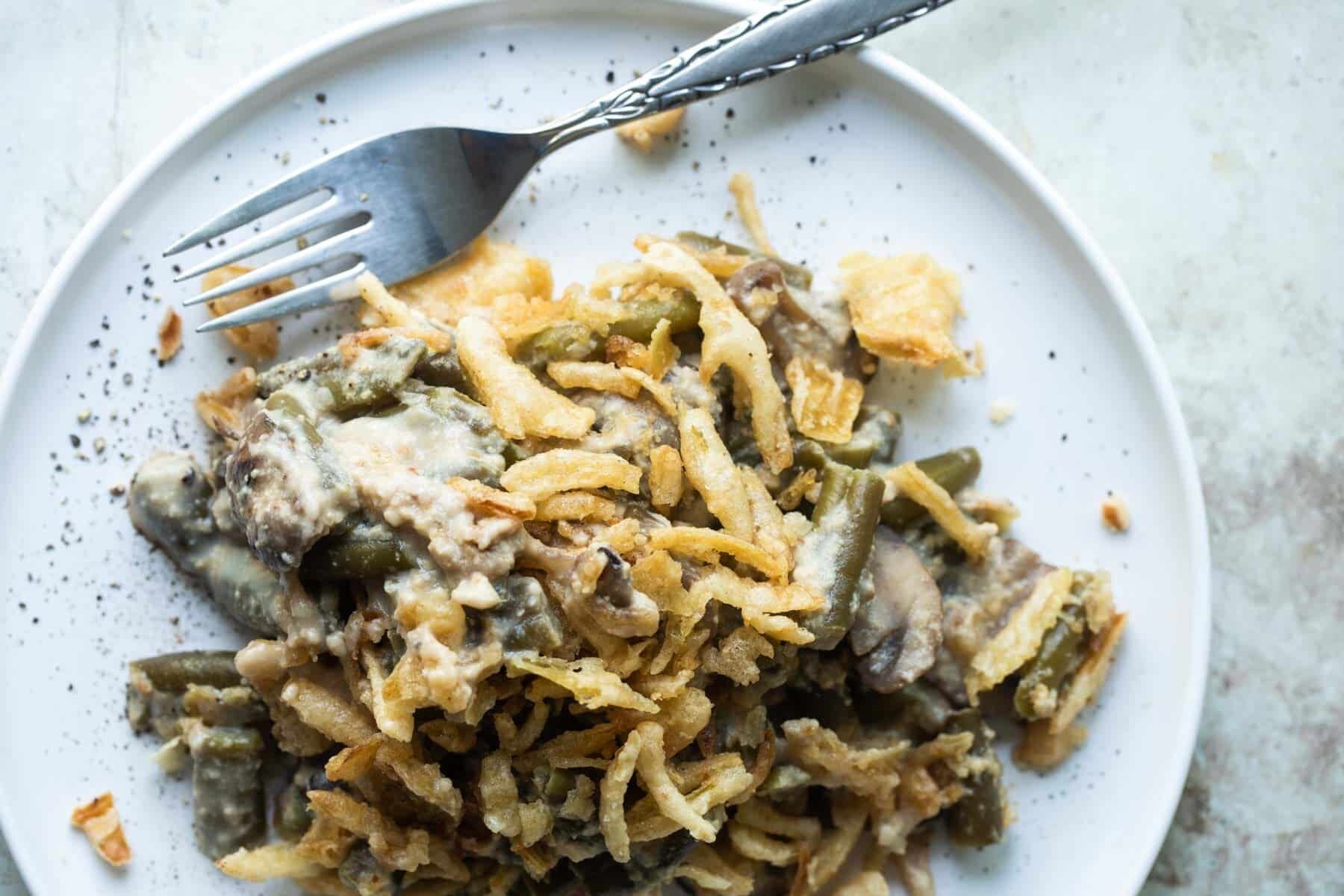 Vegan green bean casserole on a plate with a fork.