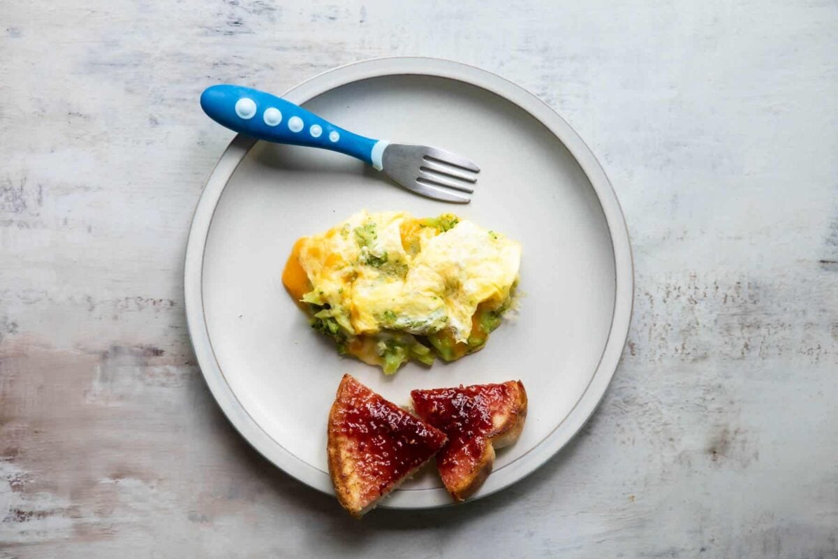 A plate with scrambled eggs and toast with jelly on it.