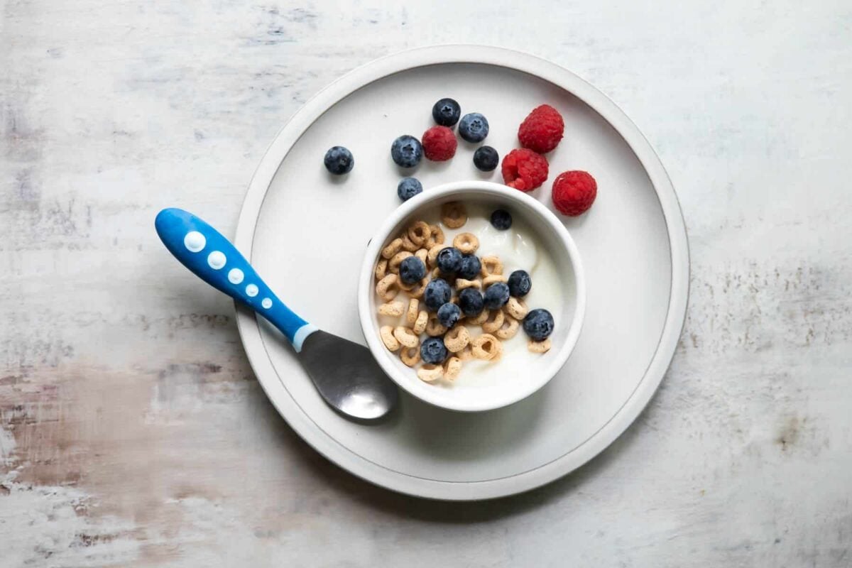 A plate with a cereal parfait and berries on it.