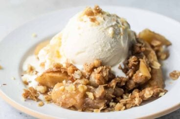 A plate of apple crisp topped with vanilla ice cream.