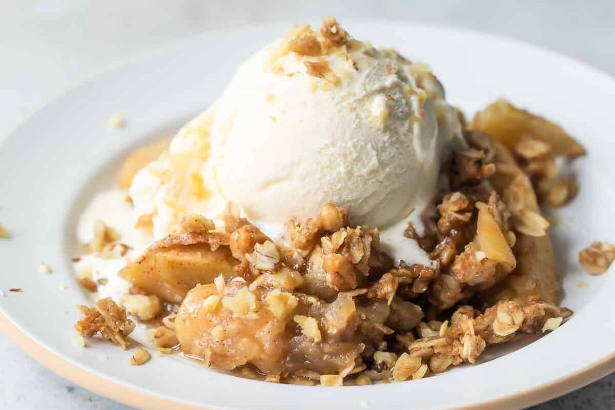 A plate of apple crisp topped with vanilla ice cream.