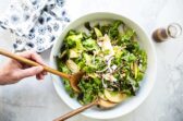 Someone scooping apple walnut salad out of a serving bowl.