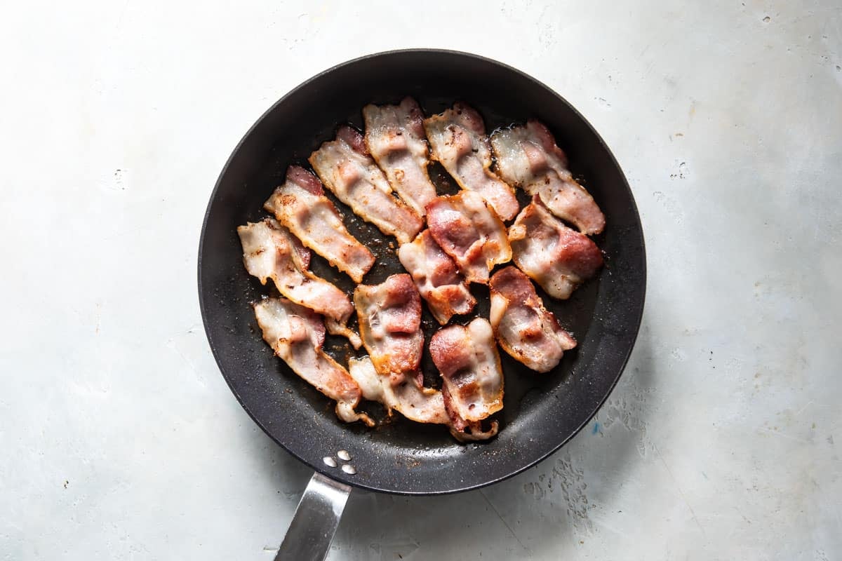 Bacon cooking in a skillet.