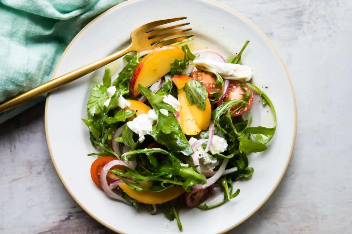 A plate of burrata salad with peaches.