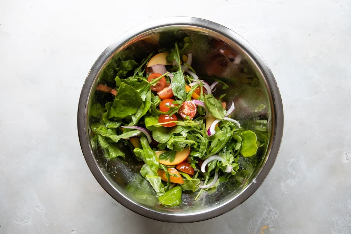 A bowl of burrata salad dressed with vinaigrette.