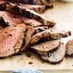 A cutting board with a sliced tri tip on top.