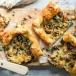 Slices of mushroom and leek tart strewn with fresh thyme.