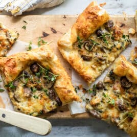 Slices of mushroom and leek tart strewn with fresh thyme.