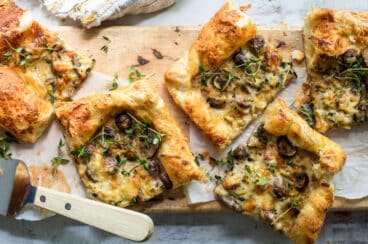 Slices of mushroom and leek tart strewn with fresh thyme.