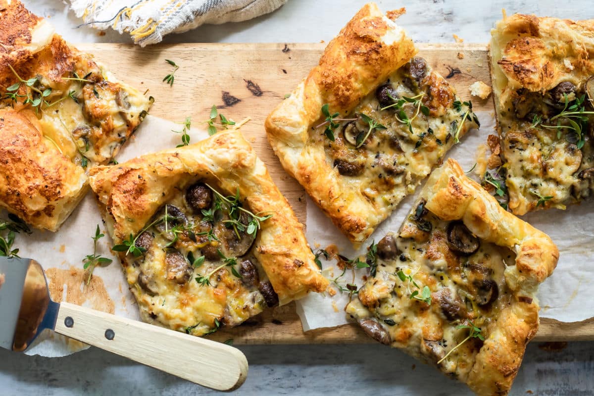 Slices of mushroom and leek tart strewn with fresh thyme.