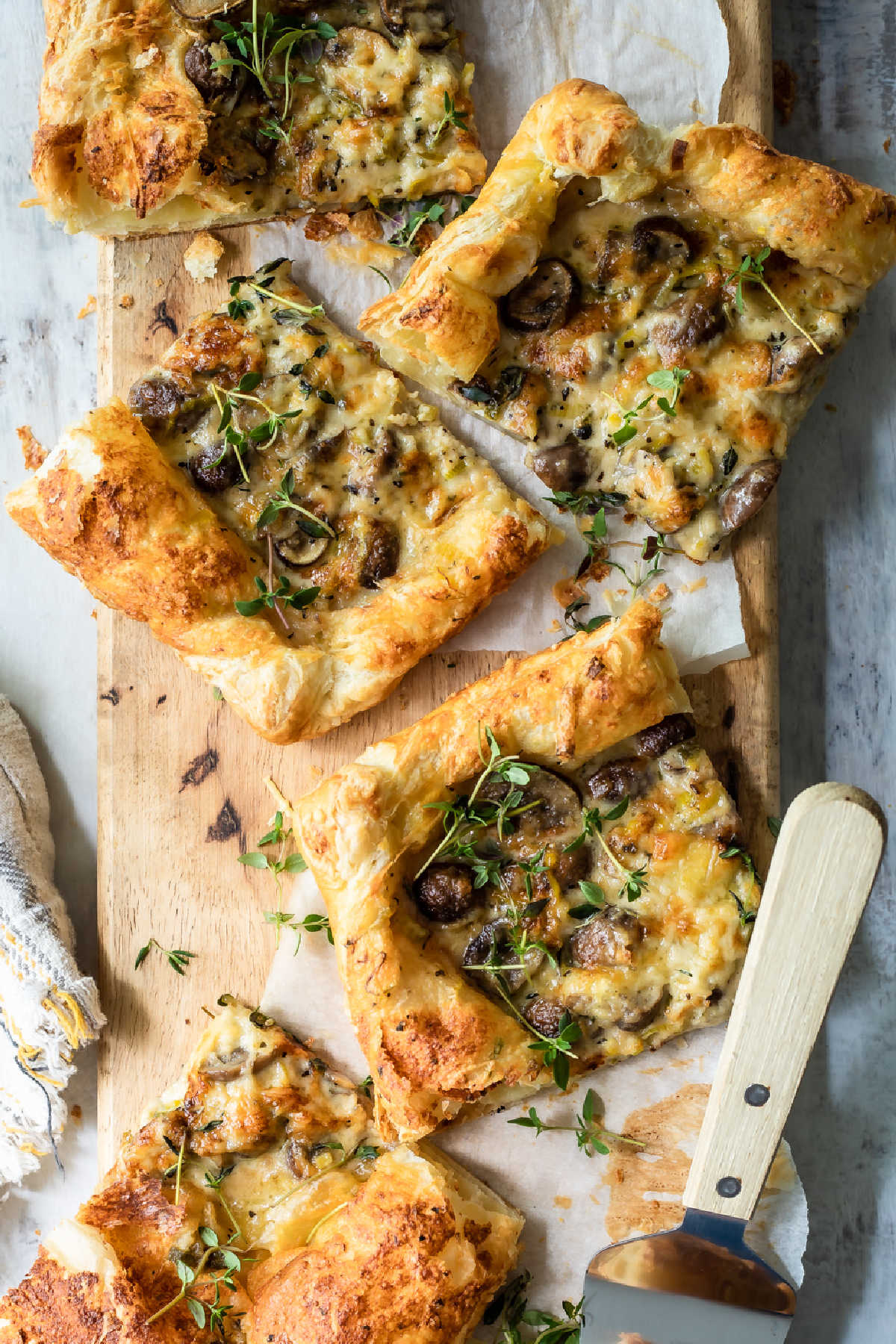 Slices of mushroom and leek tart strewn with fresh thyme.