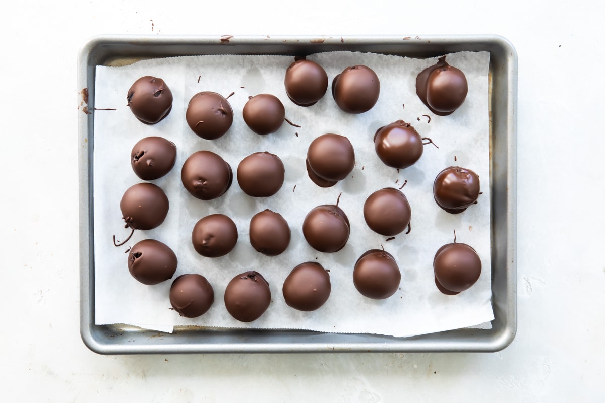 Oreo cookie balls chilling on a baking sheet.