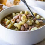 Slow cooker pasta and bean soup in a white bowl.