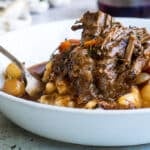 A white bowl of beef bourguignon and mashed potatoes.