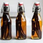 Three bottles of vanilla extract on a countertop.