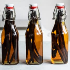Three bottles of vanilla extract on a countertop.