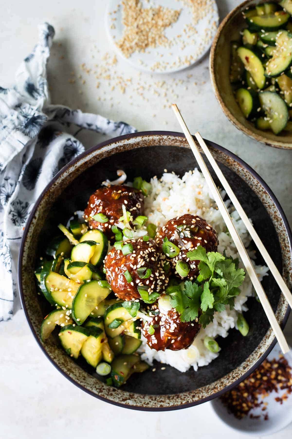 Korean barbecue meatballs, rice and cucumber in a gray bowl