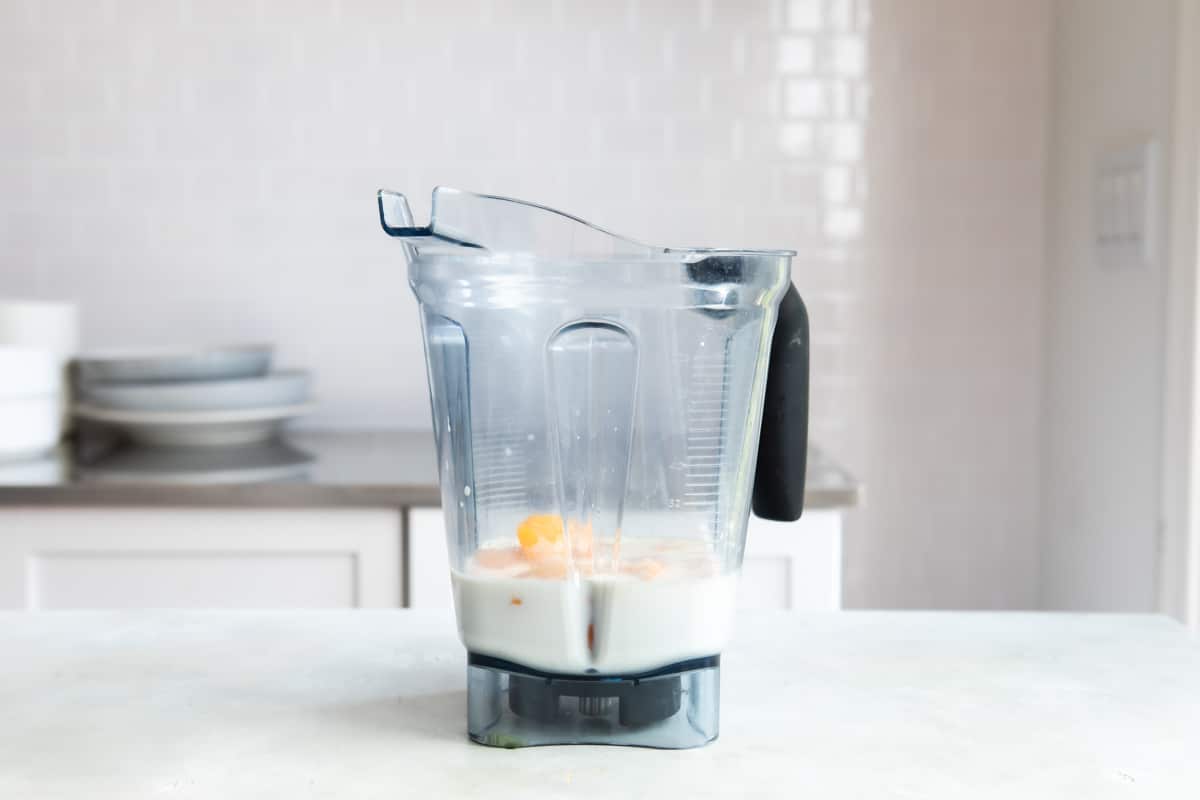 Peach smoothie ingredients in a blender.