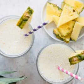 2 Pineapple Smoothies in glasses with striped straws.