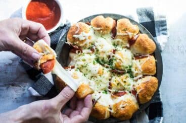 A pan of pull-apart pizza bread served with marinara.