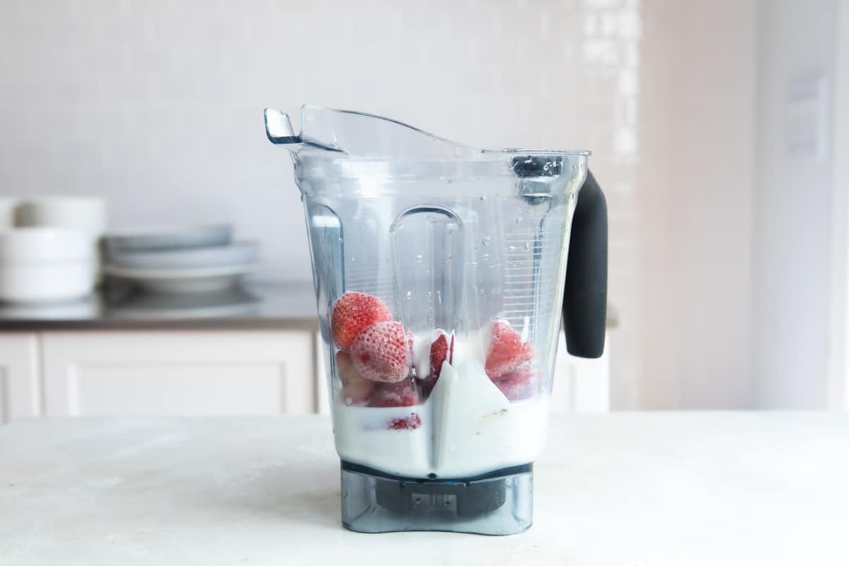 A blender with strawberry-banana smoothie ingredients inside.