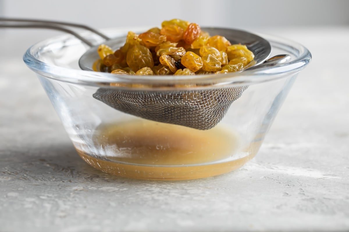 Soaking golden raisins in liquid to plump.