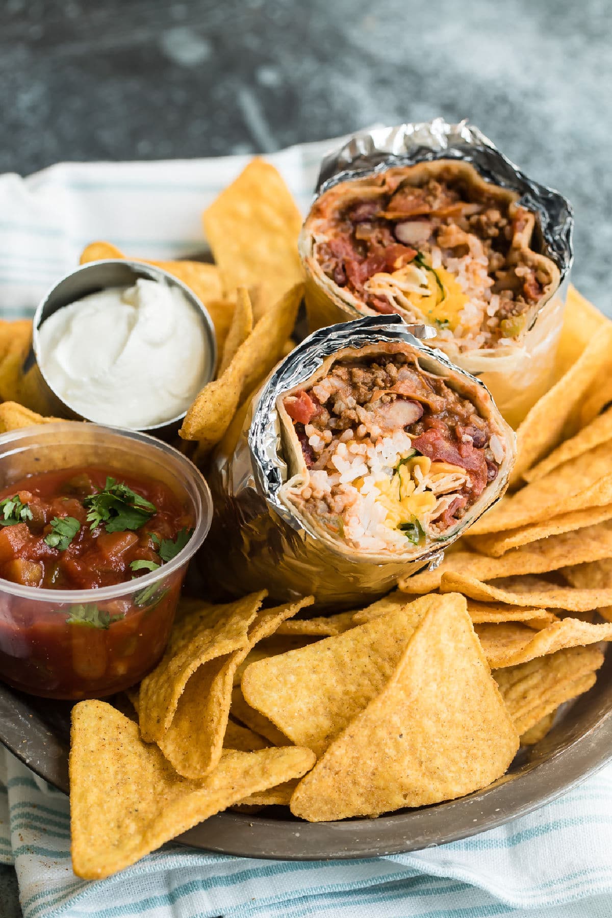 A chili cheese burrito sliced open to show the insides on a pile of tortilla chips.