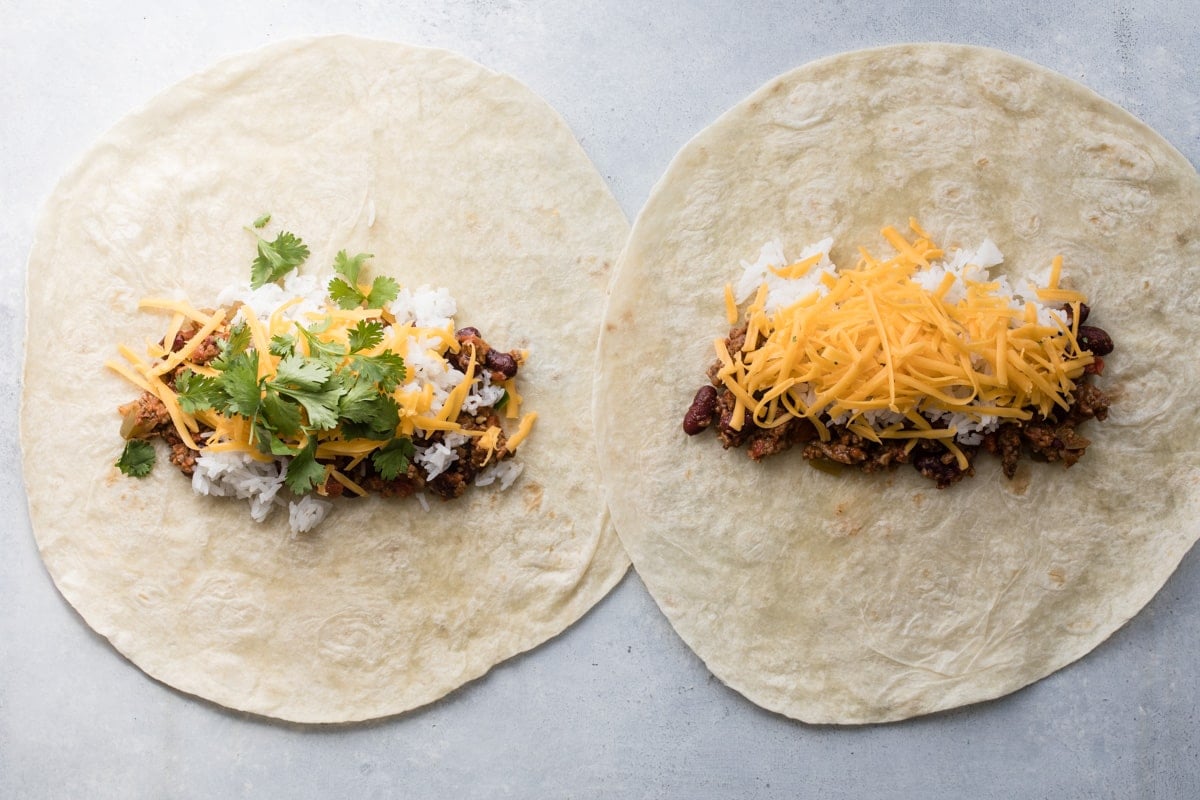 Chili, rice, cheese, and cilatnro on flour tortillas for burritos.