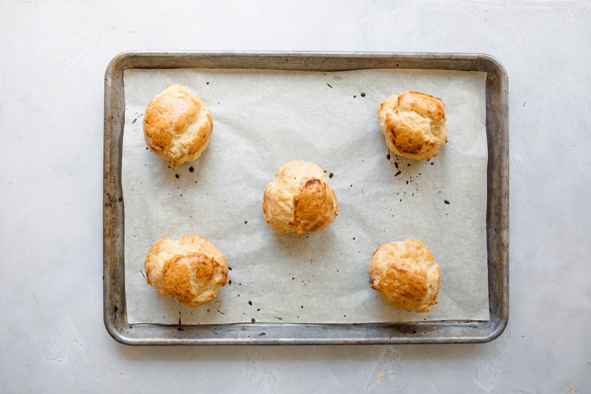 Baked cream puffs on a baking sheet.