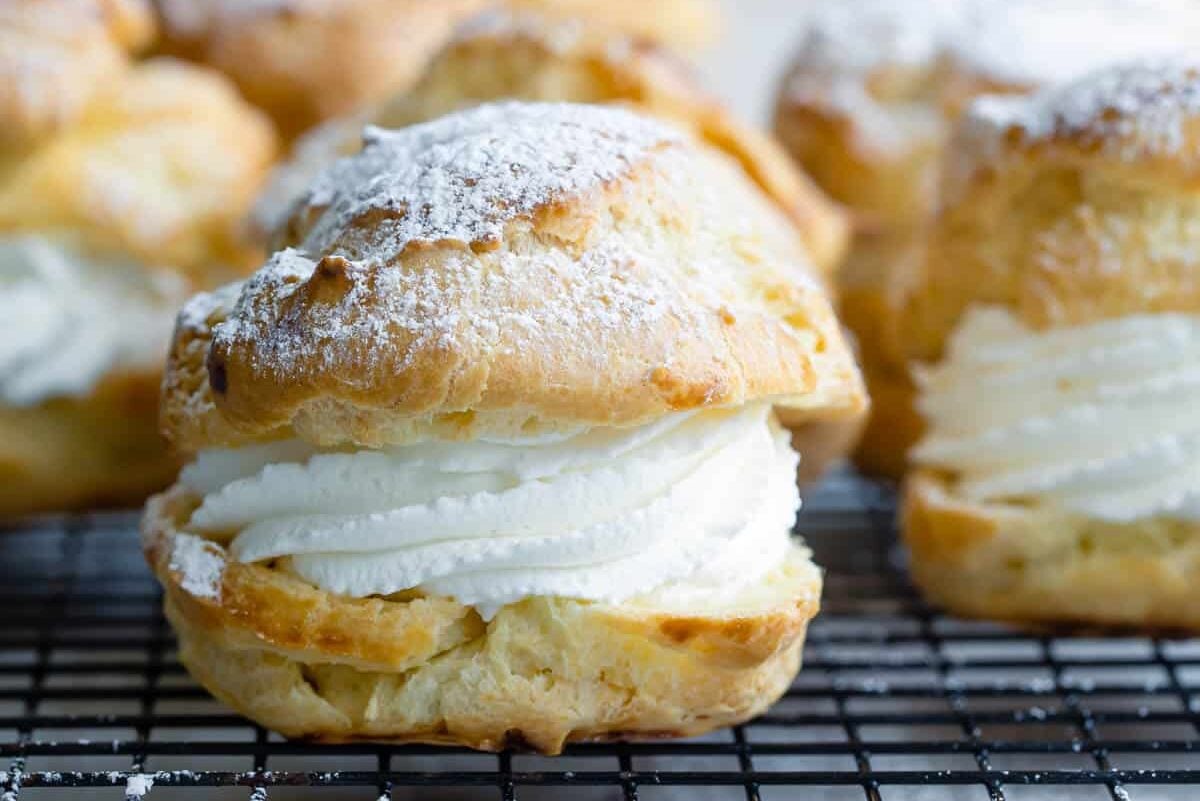 A baking rack full of filled cream puffs.