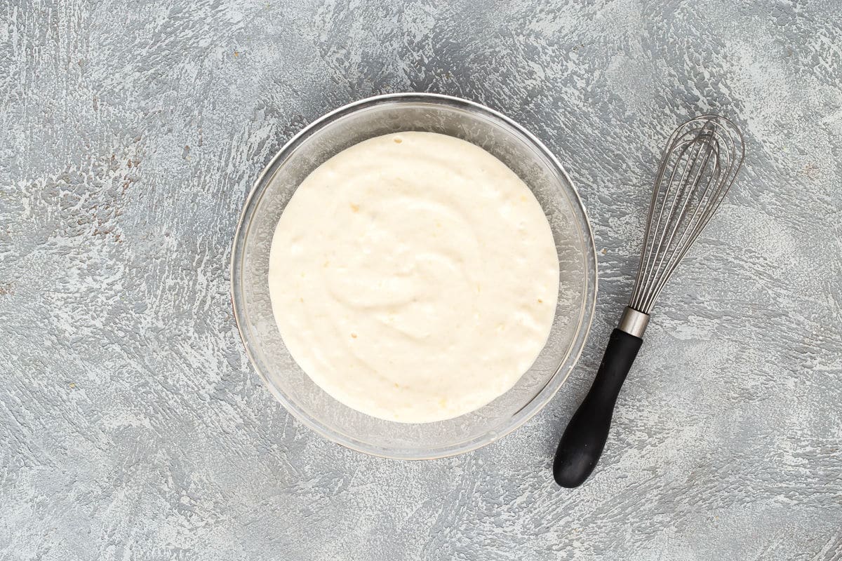Batter for lemon ricotta pancakes in a clear bowl.