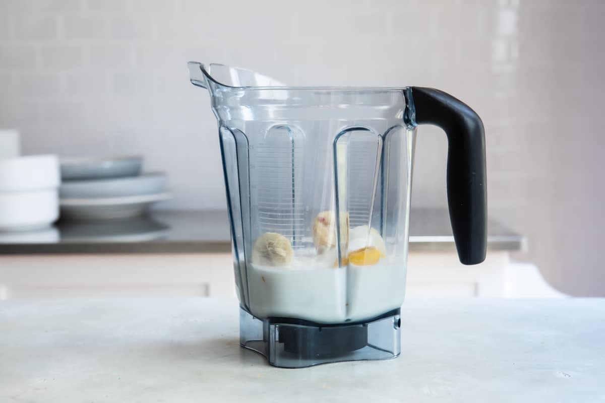 Ingredients for a mango smoothie in a blender.