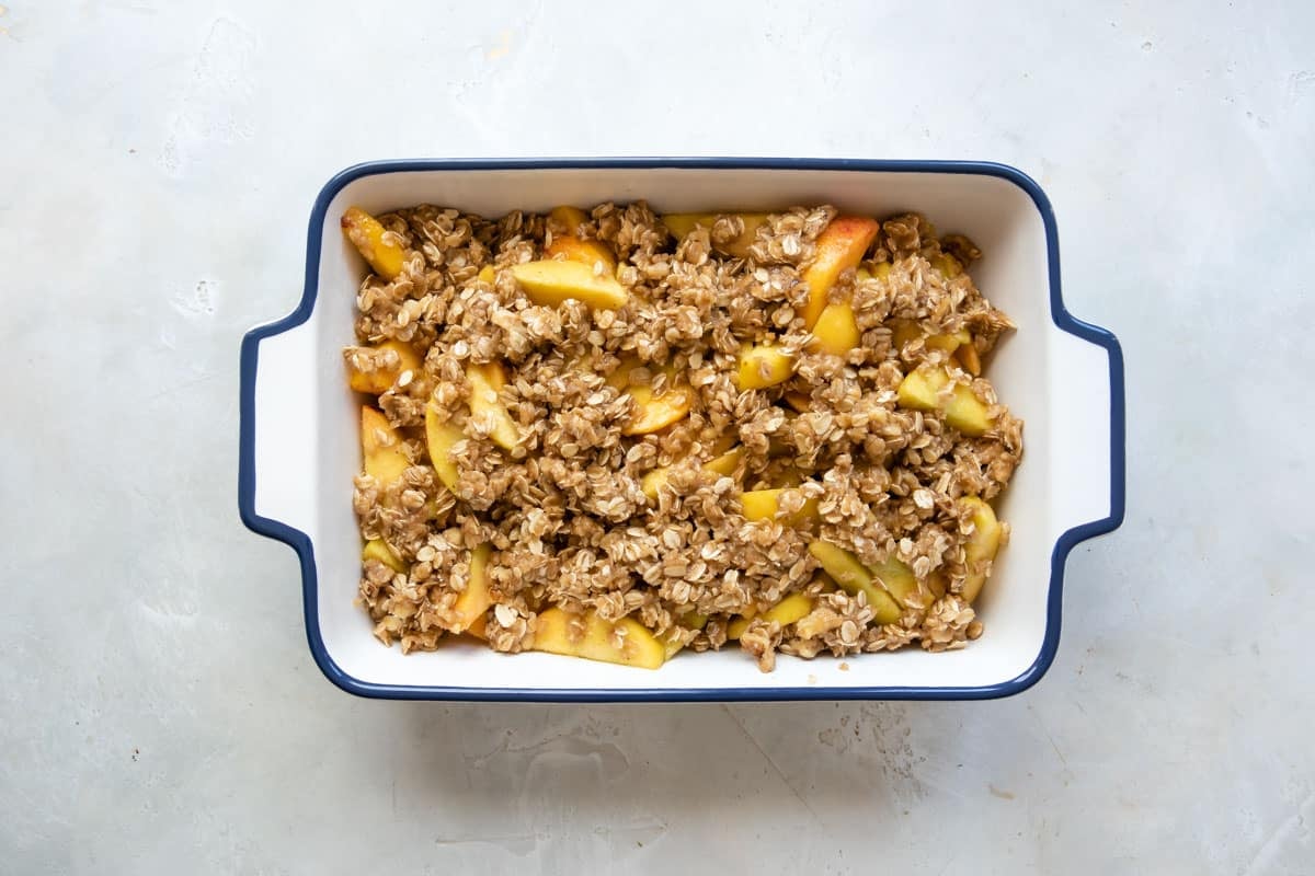 An unbaked peach crisp assembled in a baking dish.