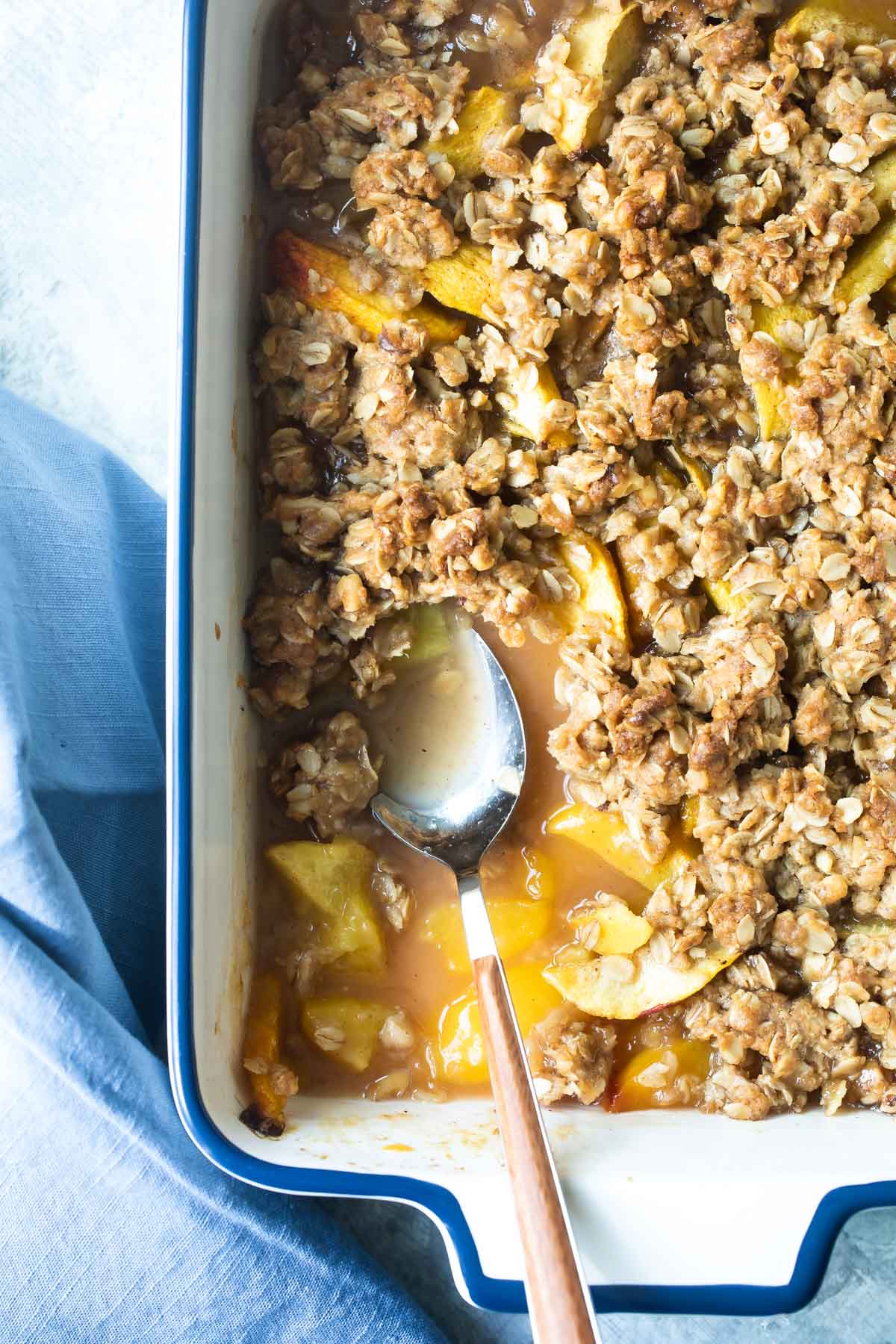 A fully baked peach crisp in a white baking dish.