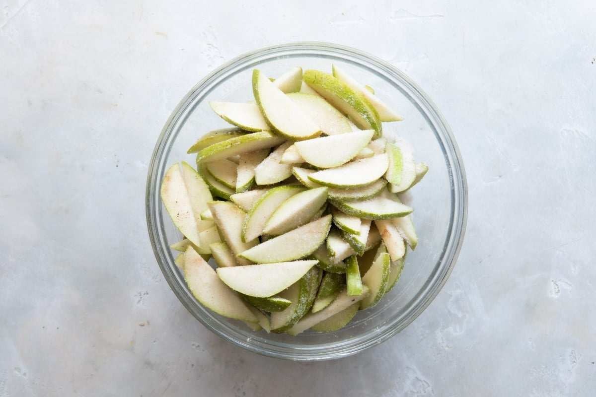 A bowl of pears tossed with cinnamon and sugar.