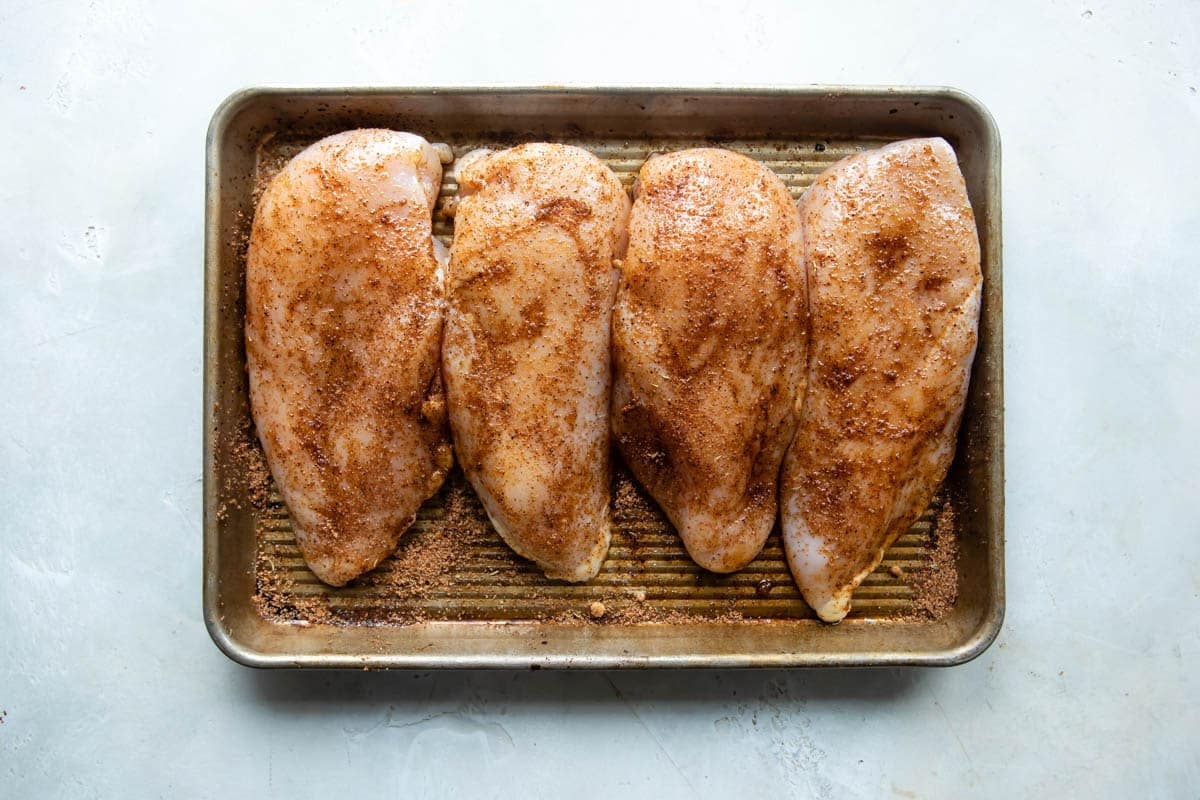 An angled shot of uncooked chicken on a sheet tray.