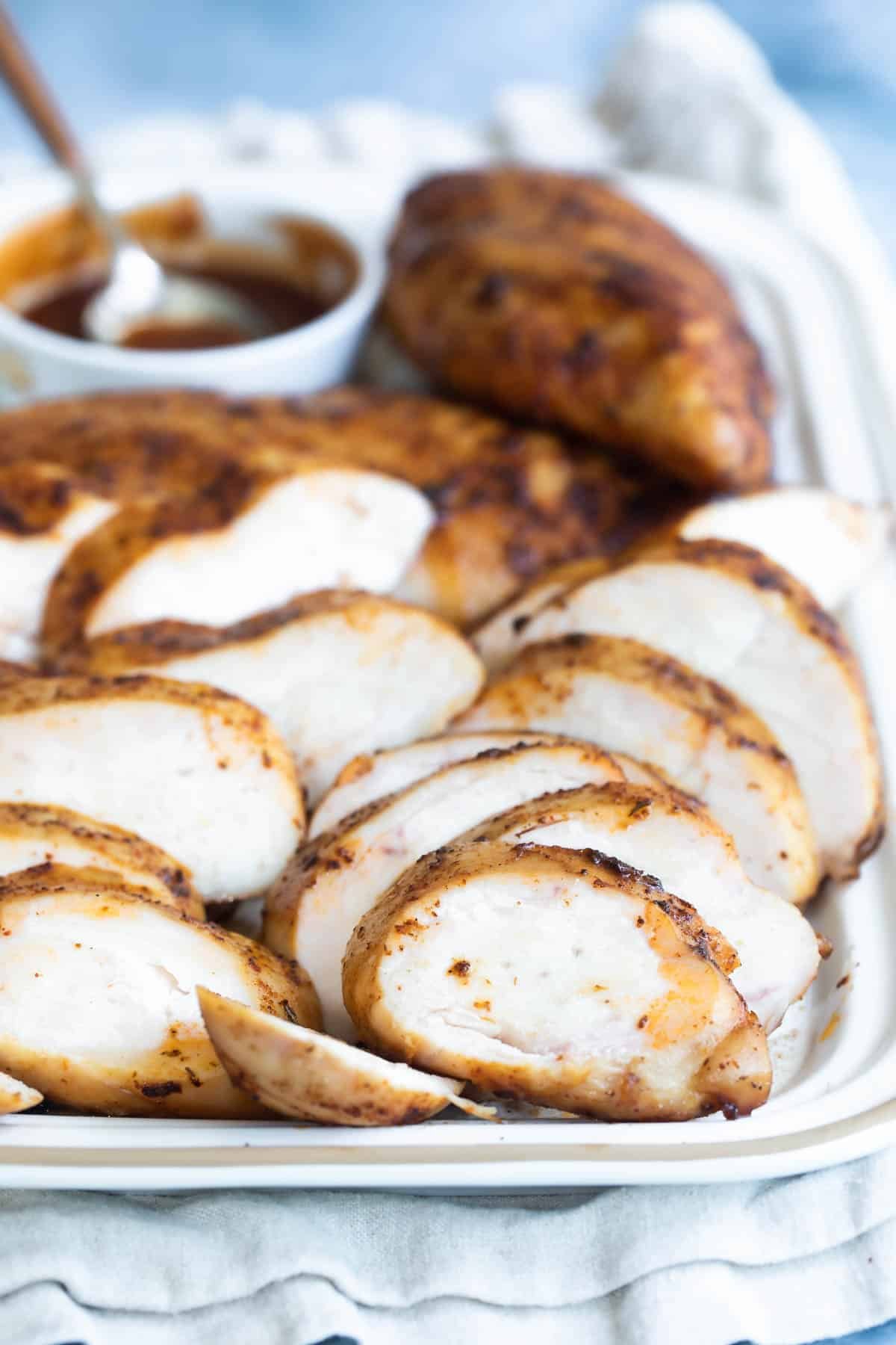 A tray of sliced smoked chicken breast with bbq sauce.