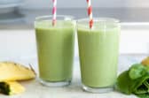 2 glasses of Spinach Smoothie with ingredients nearby.