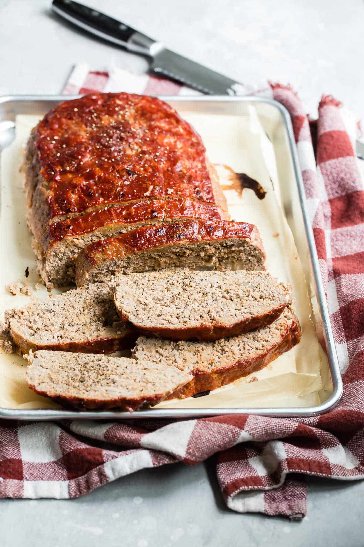 A turkey meatloaf with slices cut off on a baking sheet.