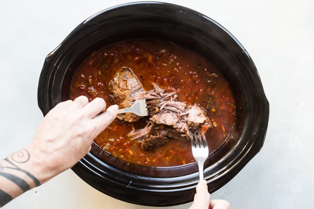Shredded beef in a slow cooker for beef ragu.