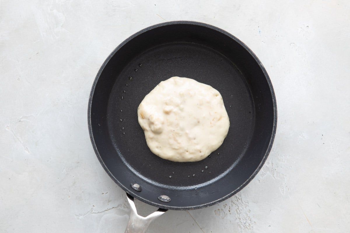 Pancake batter in a skillet before flipping.